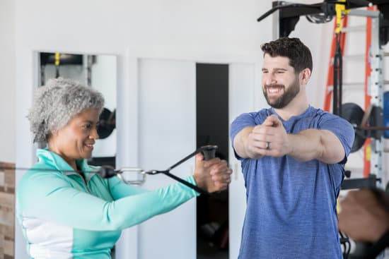 Fitness Blender Feel Good Stretching Routine: Relaxed woman stretching in a sunny gym